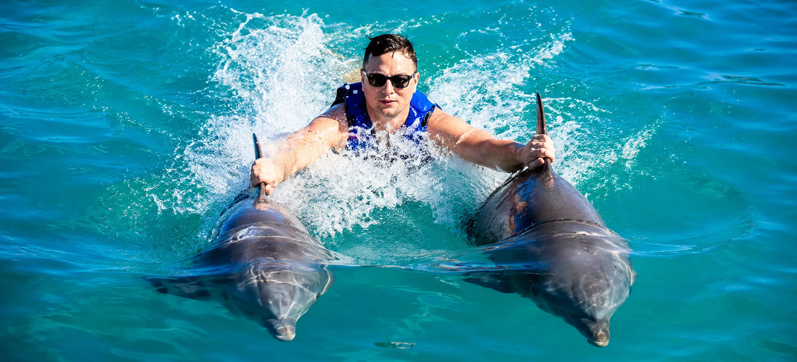 Guest riding with two dolphins during Dolphin Excellence experience in Punta Cana
