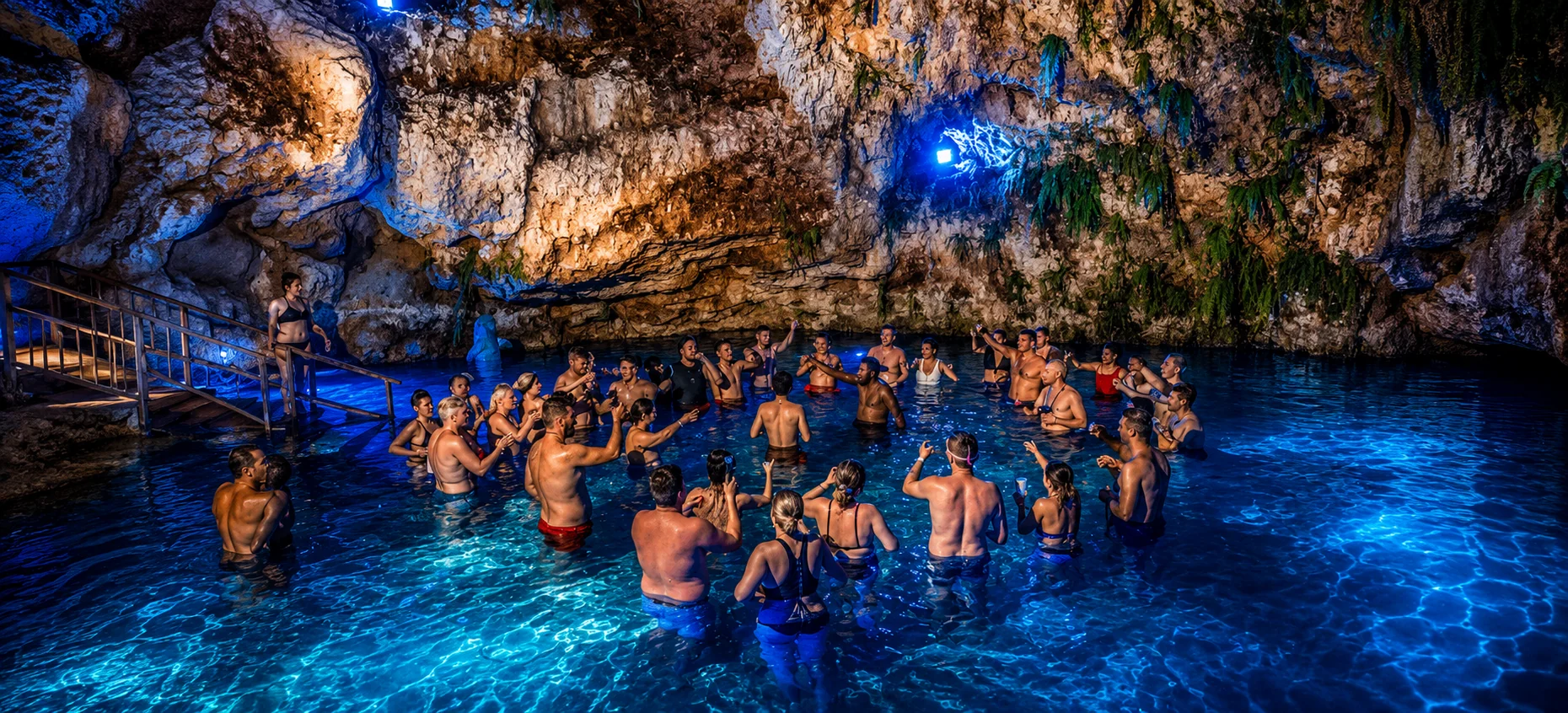 Guests swimming in the illuminated Blue Cave at Domitai Park in Punta Cana.